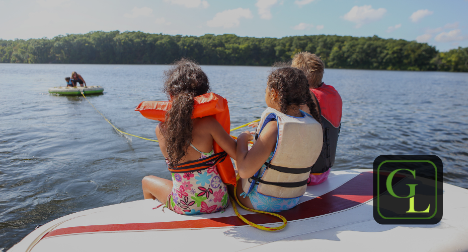 kids on a boat wearing life jackets doing water sports on a lake